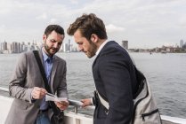 Two businessmen reviewing document on ferry on East River, New York City, USA — Stock Photo