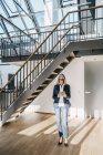 Donna d'affari con lunghi capelli grigi utilizzando tablet in un loft — Foto stock