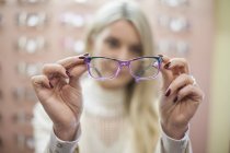 Mujer rubia seleccionando nuevas gafas en la tienda de ópticas - foto de stock