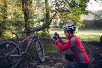 Motociclista maschio scattare foto di mountain bike in natura — Foto stock