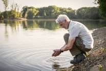 Uomo anziano rinfrescante a un lago — Foto stock