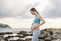 Femme enceinte debout en mer et touchant le ventre — Photo de stock