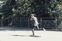 Young funky man skateboarding on bridge — Stock Photo
