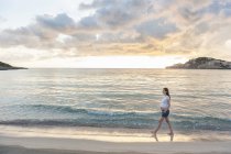 Pregnant woman walking on beach at sunrise — Stock Photo