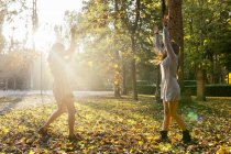 Dois melhores amigos do sexo feminino jogando-se folhas de árvore no parque no outono — Fotografia de Stock