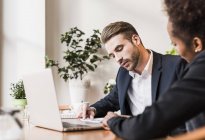 Young businessman and woman using laptop — Stock Photo