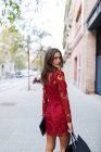 Hermosa mujer joven con vestido rojo llevando bolsas de compras - foto de stock