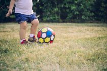Niño jugando fútbol en un prado, vista parcial - foto de stock
