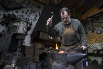 Schmied in seiner Werkstatt beim Hämmern von Metalldetails — Stockfoto