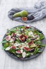 Plate of baby chard salad with pear, figs, walnuts and feta on wood surface — Stock Photo
