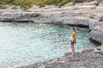 Schwangere steht an Felsküste auf See — Stockfoto