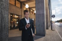 Geschäftsmann schaut abends aufs Smartphone — Stockfoto