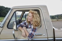 Lächelnde Frau sitzt in Transporter in der Natur — Stockfoto