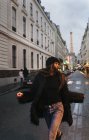 Франция, Париж, молодая женщина на улице с Эйфелевой башней на заднем плане — стоковое фото