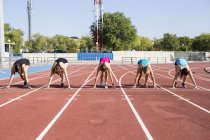 Female runners on tartan track in starting position at stadium — Stock Photo