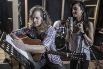 Singer and guitarist in musical recording studio — Stock Photo