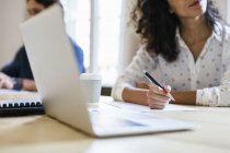 Businesswoman sitting in meeting, taking notes with a ballpen — Stock Photo