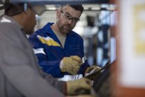 Due riparatori di pneumatici con appunti in fabbrica — Foto stock
