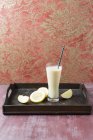 Verre de smoothie à la banane avec pomme et citron sur planche de bois — Photo de stock