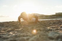 Спортсмен отжимается на песчаном пляже — стоковое фото