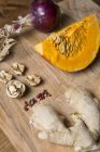 Pumpkin, onions, walnuts and ginger on chopping board — Stock Photo
