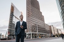 Усміхаючись бізнесмен стоять біля Потсдамської площі з смартфон — стокове фото