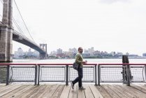 USA, New York City, man walking at East River with coffee to go — Stock Photo