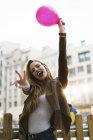 Ritratto di giovane donna felice con palloncino che mostra il segno della vittoria — Foto stock