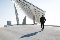 Empresario caminando con panel solar sobre fondo, Barcelona, España - foto de stock