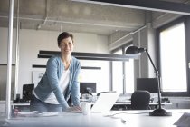 Retrato de empresária confiante com laptop em pé no escritório — Fotografia de Stock