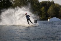 Casal wakeboarding com salpicos no lago no verão — Fotografia de Stock