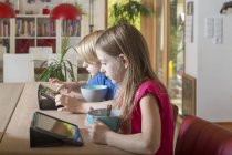 Jungen und Mädchen mit Tabletten am Frühstückstisch — Stockfoto