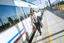 Attraente donna caucasica a piedi sul binario accanto al treno — Foto stock
