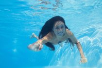Lächelnde junge Frau unter Wasser in einem Pool — Stockfoto