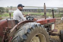 Agriculteur mâle avec capuchon conducteur tracteur à la ferme — Photo de stock