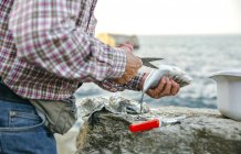 Uomo anziano taglio pesce catturato — Foto stock