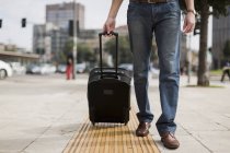 Ноги бізнесмена з валізою на тротуарі — стокове фото