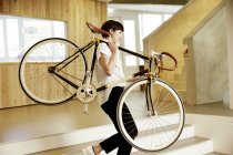Donna che porta il ciclo di corse sulla spalla in un ufficio — Foto stock