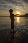 Ragazzo che si tiene per mano contro il sole, al tramonto — Foto stock
