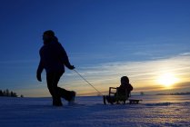 Mother and daughter sledging at sunset in nature — Stock Photo