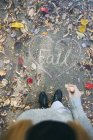 Adolescente de pie en el camino con hojas de otoño y caída de la palabra — Stock Photo