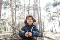 Portrait of little boy playing with branch in the woods — Stock Photo