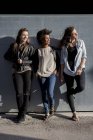 Drei junge Frauen lehnen an Wand — Stockfoto