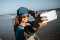 Young woman taking a selfie on the beach — Stock Photo