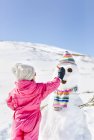 Rear view of girl building snowmen in at snow in winter — Stock Photo
