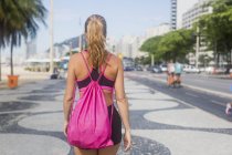 Бразилия, Рио-де-Жанейро, вид сзади женщины, идущей по тротуару — стоковое фото