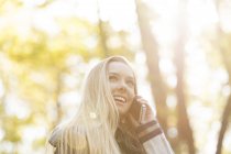 Smiling teenage girl on cell phone in autumn — Stock Photo