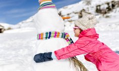 Happy girl playing with snowmen in winter — Stock Photo