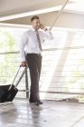 Businessman with luggage and cell phone — Stock Photo