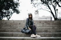 Sonriente joven sentada en las escaleras - foto de stock